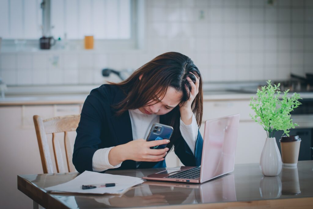 スマホを眺めながら不倫相手に連絡を使用かどうか迷っている女性の写真